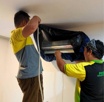PrimeChem technicians cleaning a wall-mounted split-type AC unit with a waterproof service bag