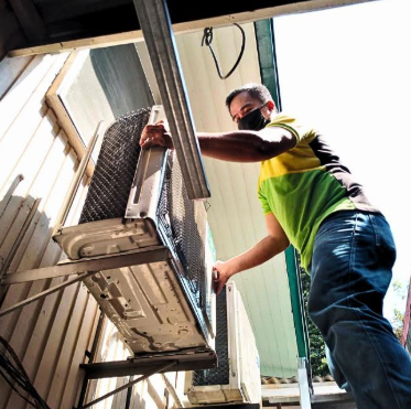 PrimeChem technician maintaining an outdoor air-conditioning condenser